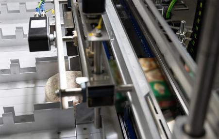 Zufuhr von Tiefkühlpizzen in Schachtel der Verpackungsmaschine HC-S von miropack